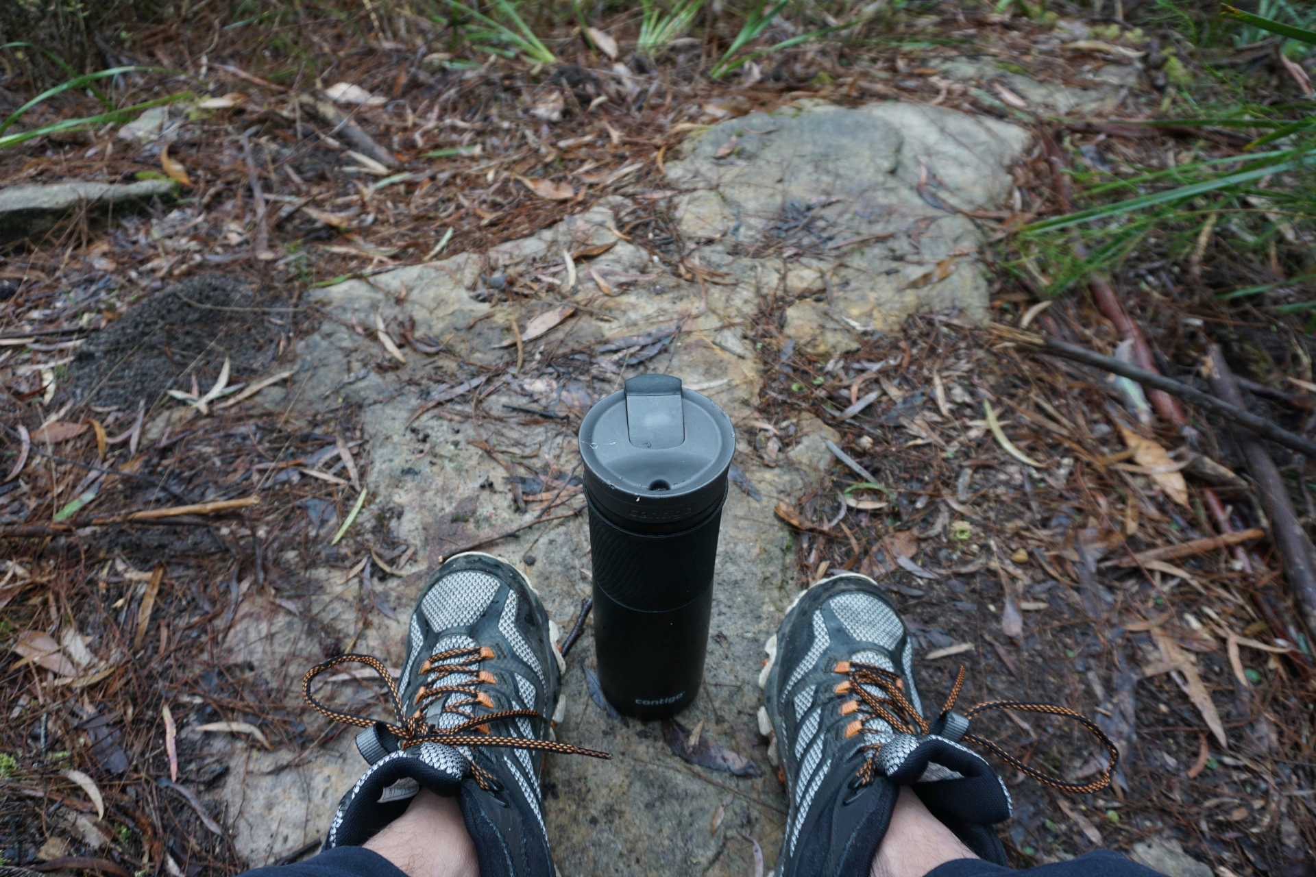 First person view from a man sitting down for a respite during a hike in the mountains with his water bottle in between his hiking boots. He sits and reflects, recent life events with family and friends.